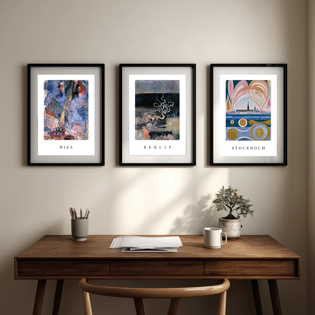 Die drei Poster Berlin, Stockholm und Wien nebeneinander über einem Schreibtisch