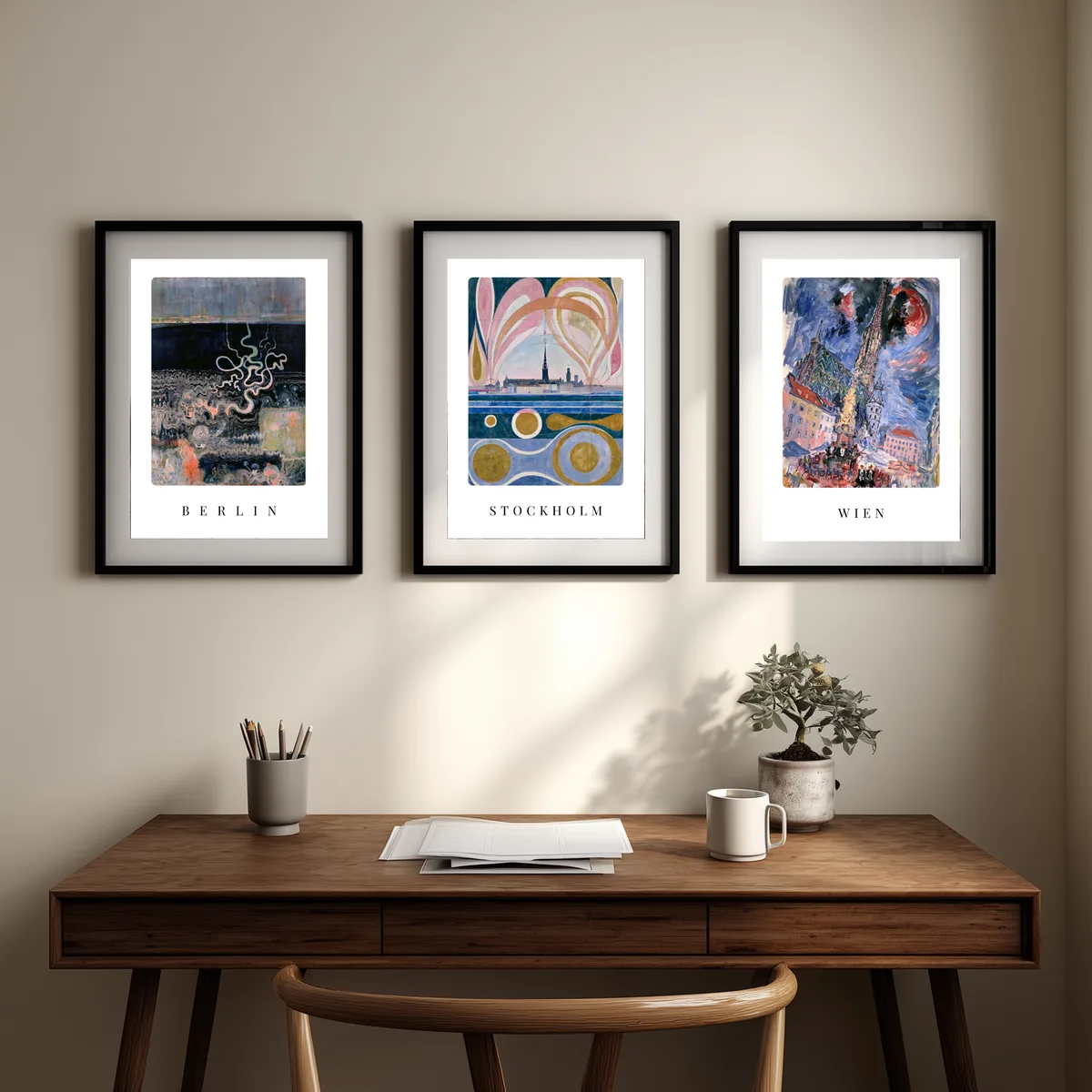 Die drei Poster Berlin, Stockholm und Wien nebeneinander über einem Schreibtisch